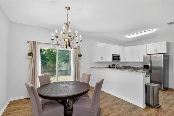 a kitchen with refrigerator a stove dining table and chairs