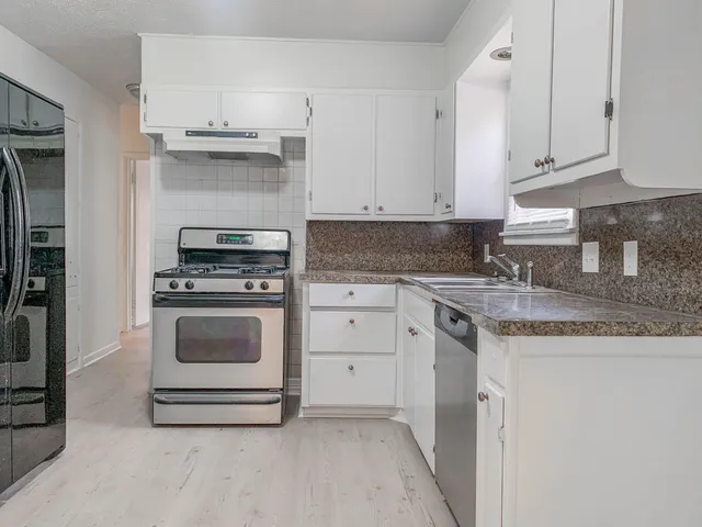 a kitchen with granite countertop a stove sink and cabinets
