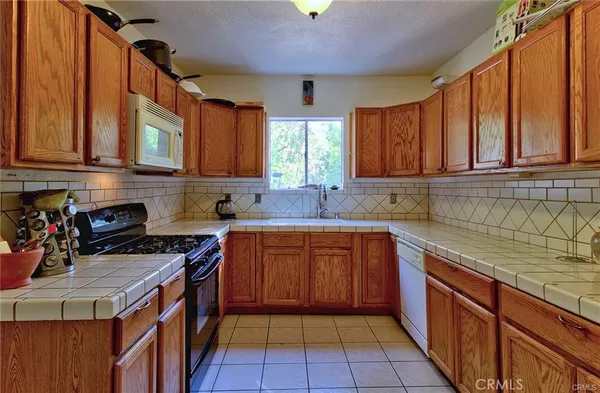 a kitchen with stainless steel appliances granite countertop a sink a stove top oven a counter space and cabinets