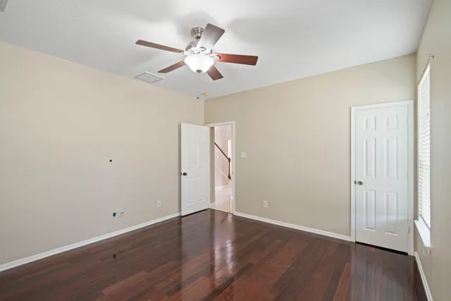 an empty room with wooden floor and ceiling fan