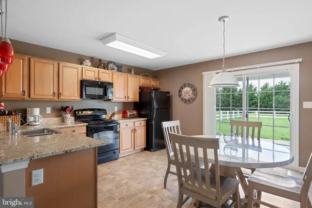 a kitchen with stainless steel appliances granite countertop a stove top oven a sink a dining table and chairs