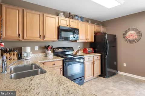 a kitchen with stainless steel appliances granite countertop a refrigerator sink and stove