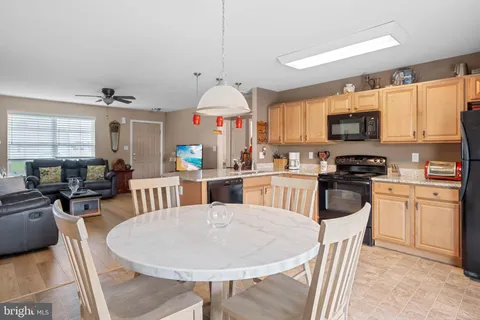 a kitchen with stainless steel appliances granite countertop a stove a refrigerator a kitchen island a dining table and chairs