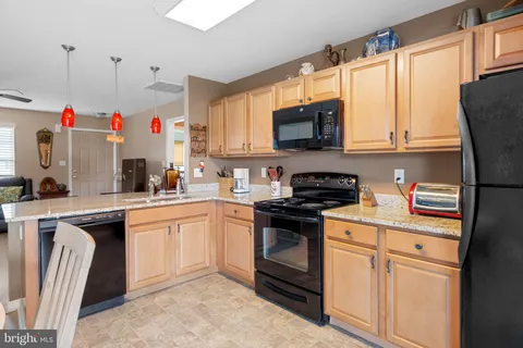 a kitchen with granite countertop stainless steel appliances sink microwave and window