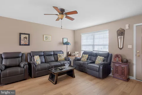a living room with furniture a ceiling fan a lamp and a window