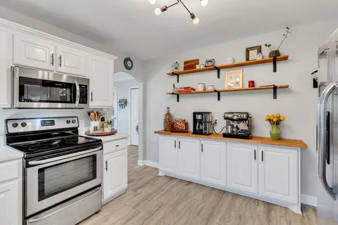 a kitchen with stainless steel appliances a white cabinets and a stove top oven