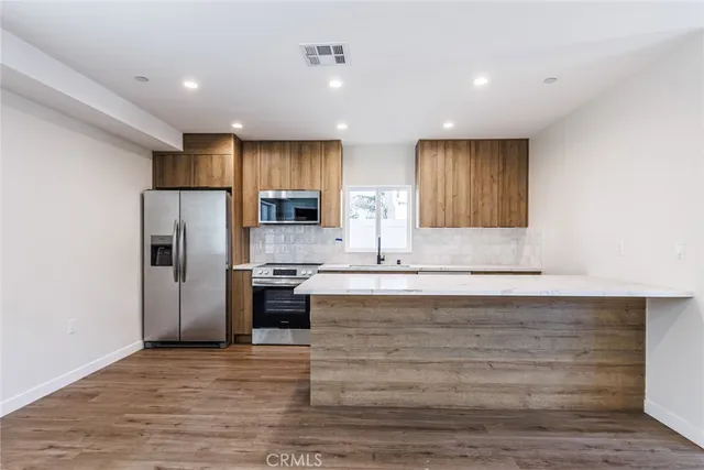 a large kitchen with kitchen island a sink stainless steel appliances and cabinets