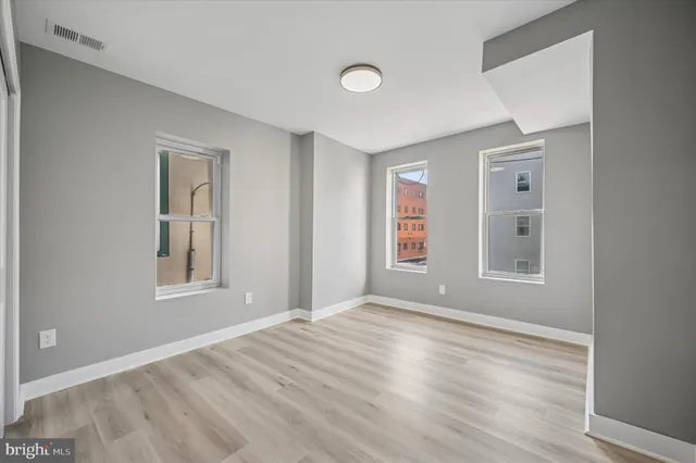 a view of an empty room with window and wooden floor