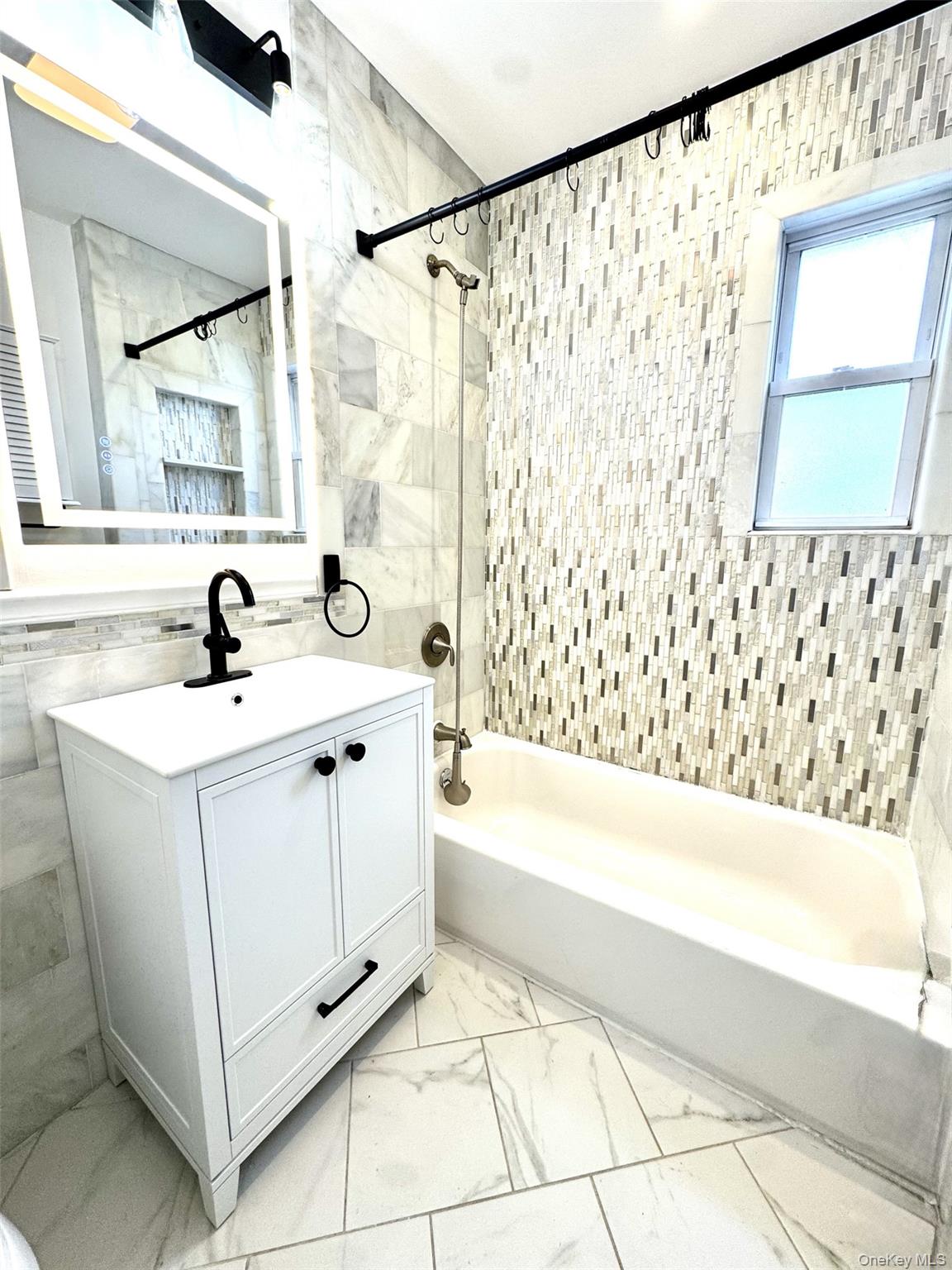 1004 Balcom Avenue Bronx, NY 10465 - Photo 2 of 14 a bathroom with a sink a bathtub and a window