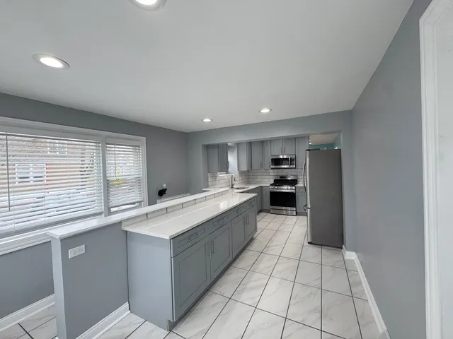 a large kitchen with a large counter top and stainless steel appliances