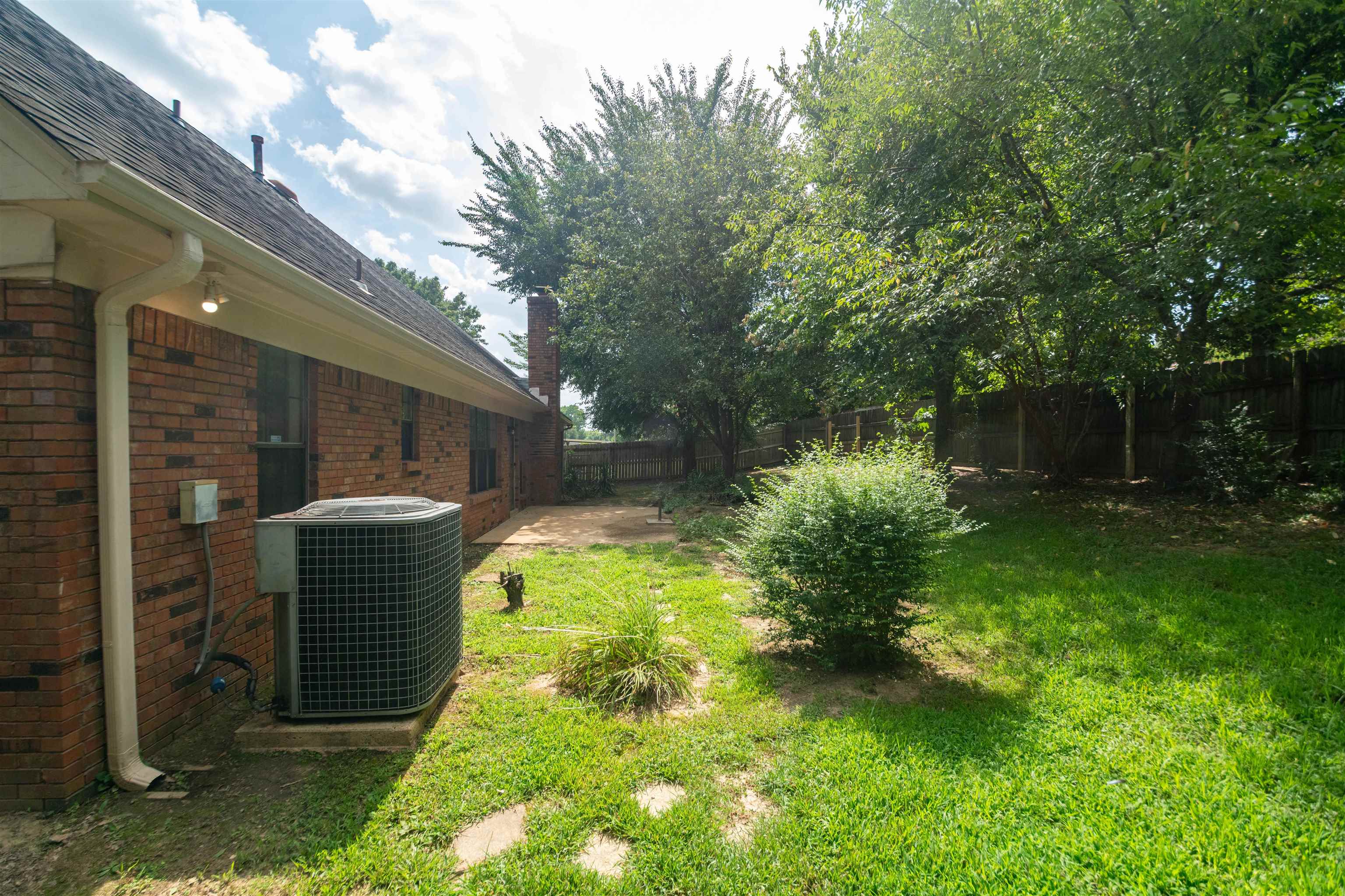 7800 Buck Ridge Cove Memphis, TN 38016 - Photo 35 of 36 Expansive backyard featuring a manicured lawn, established trees, and a concrete patio area