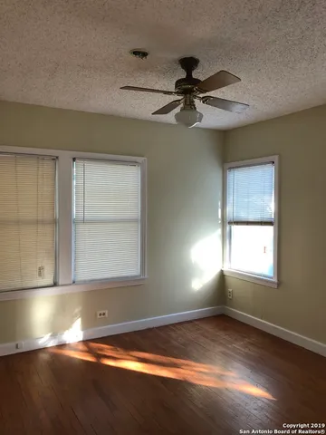 a view of empty room with wooden floor and fan
