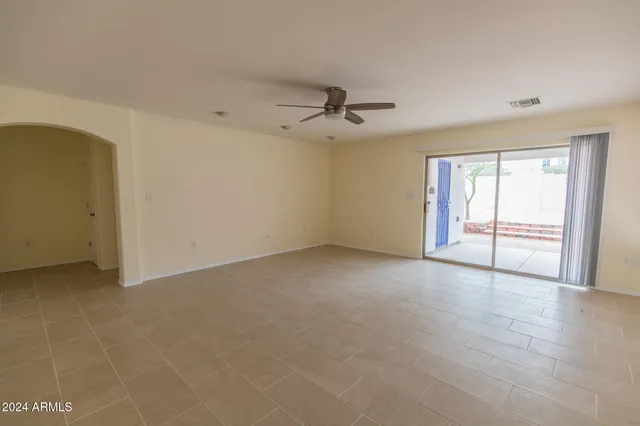 an empty room with windows and chandelier fan