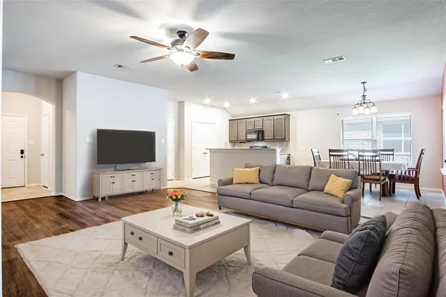 a living room with furniture kitchen view and a flat screen tv