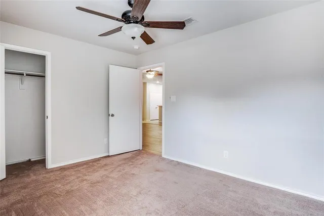 an empty room with ceiling fan and window