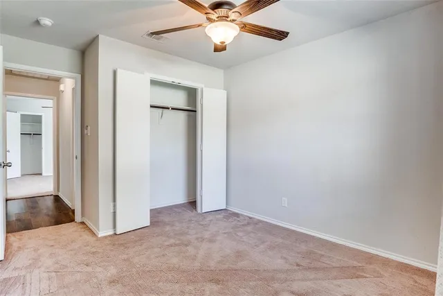 an empty room with closet and a chandelier fan