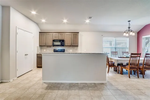 a large kitchen with cabinets chairs and stainless steel appliances
