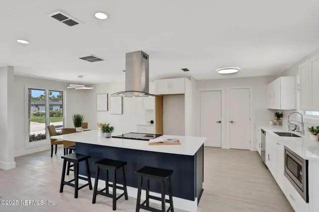 a kitchen with a dining table chairs and white cabinets