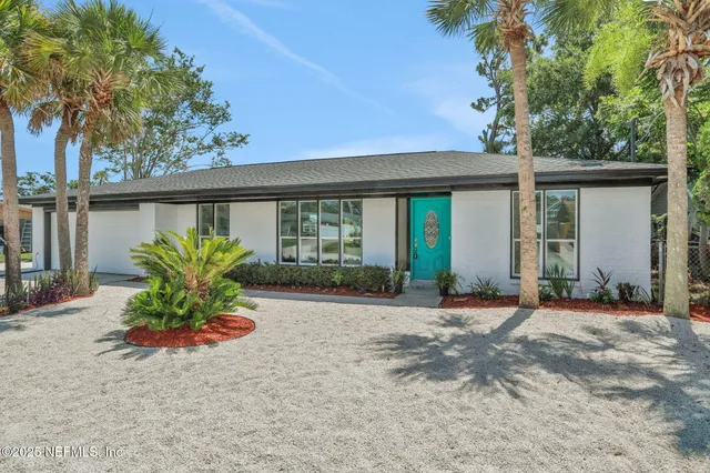 a front view of a house with a yard and potted plants