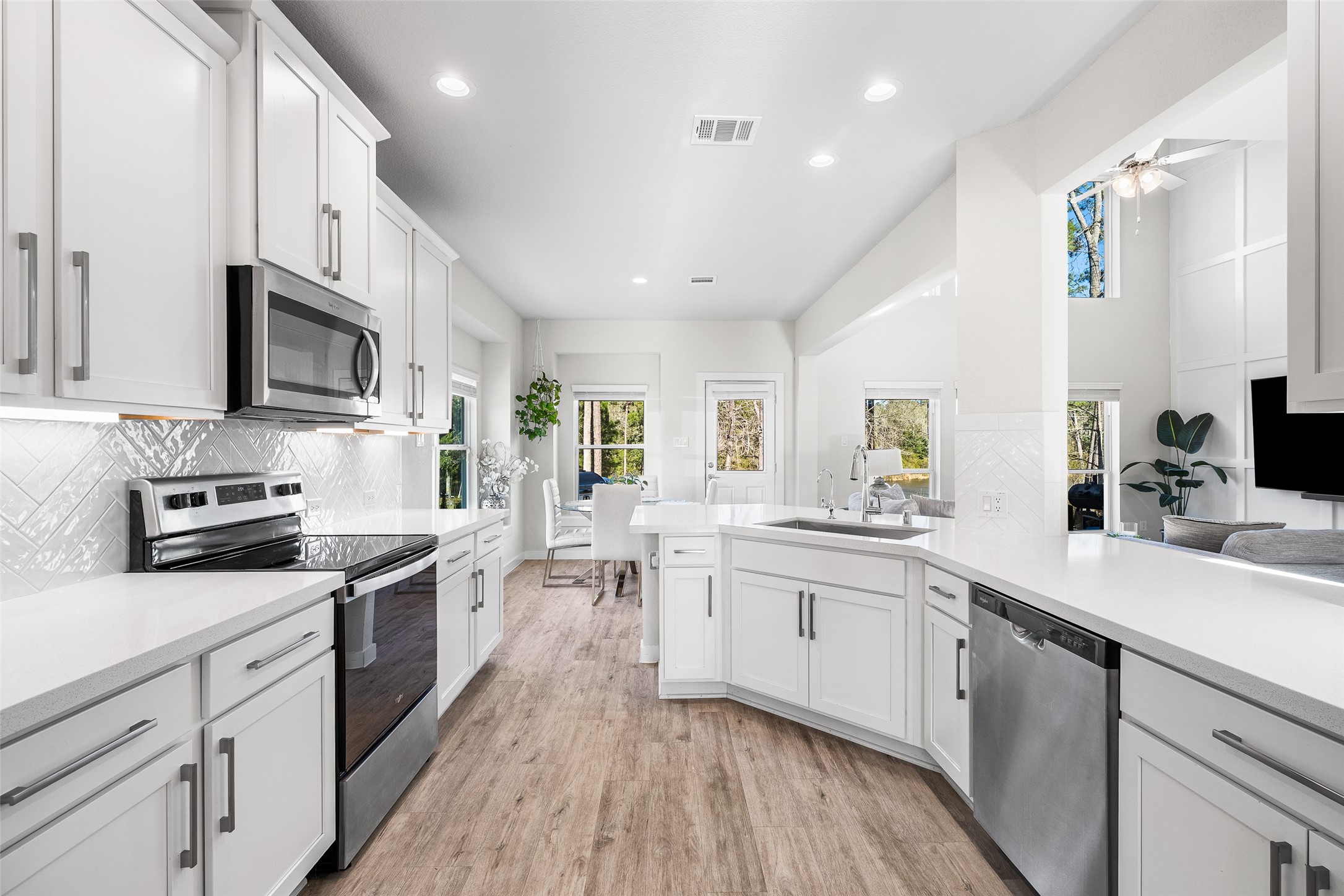 11731 Oakwood Rnch Drive Willis, TX 77378 - Photo 14 of 43 a kitchen with stainless steel appliances a sink dishwasher a stove top oven a refrigerator with white cabinets and wooden floor