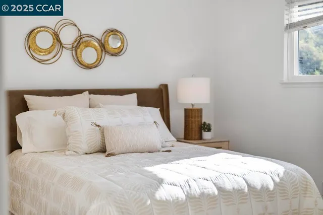 a large bed sitting in a bedroom next to a window and a lamp