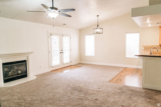 1825 West Mathis Park Place, Unit 40 St. George, UT 84770 - Photo 9 of 28 Unfurnished living room with light carpet, lofted ceiling, a ceiling fan, a glass covered fireplace, and french doors