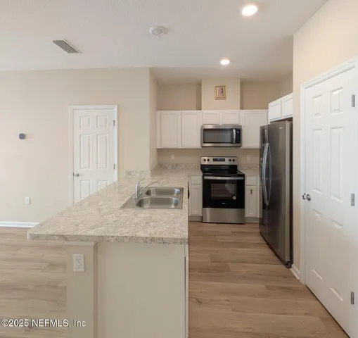 a kitchen with a refrigerator sink and cabinets