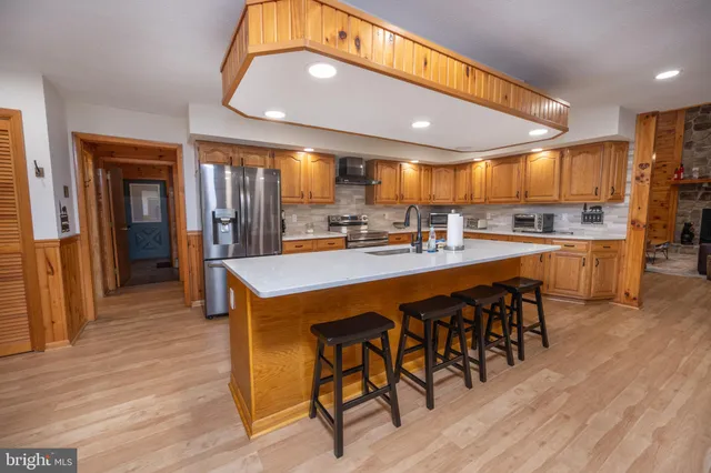 a kitchen with stainless steel appliances granite countertop a refrigerator a sink dishwasher a stove and a refrigerator with wooden floor