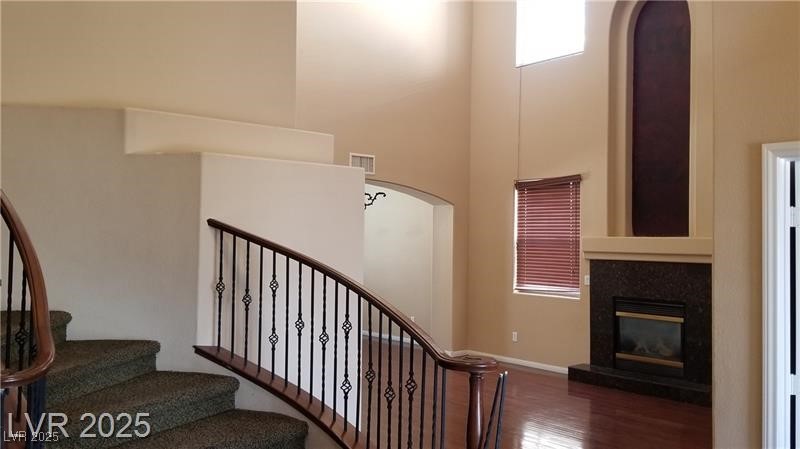 7414 Page Ranch Court Las Vegas, NV 89131 - Photo 12 of 36 Stairs with a towering ceiling, wood finished floors, a glass covered fireplace, and arched walkways
