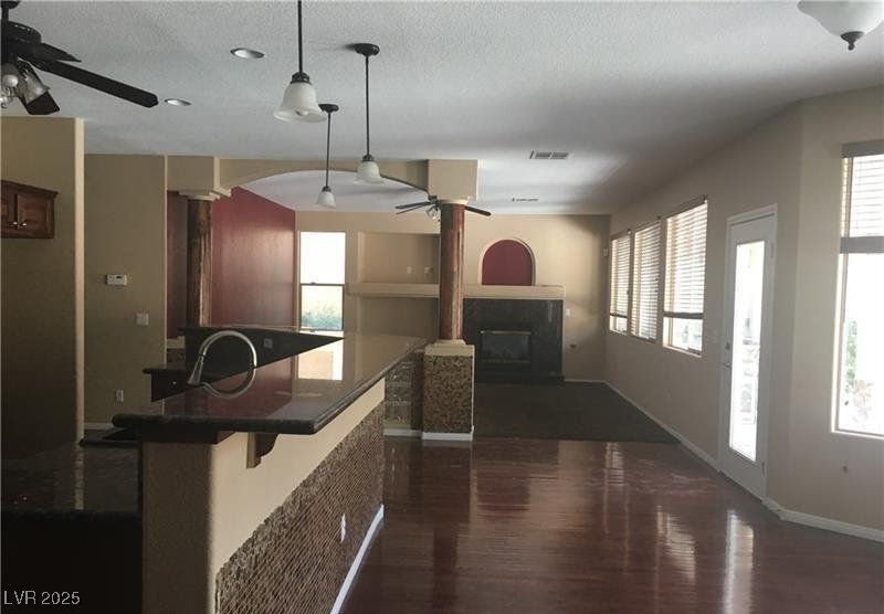 7414 Page Ranch Court Las Vegas, NV 89131 - Photo 6 of 36 Kitchen featuring a ceiling fan, dark wood finished floors, a glass covered fireplace, healthy amount of natural light, and a textured ceiling