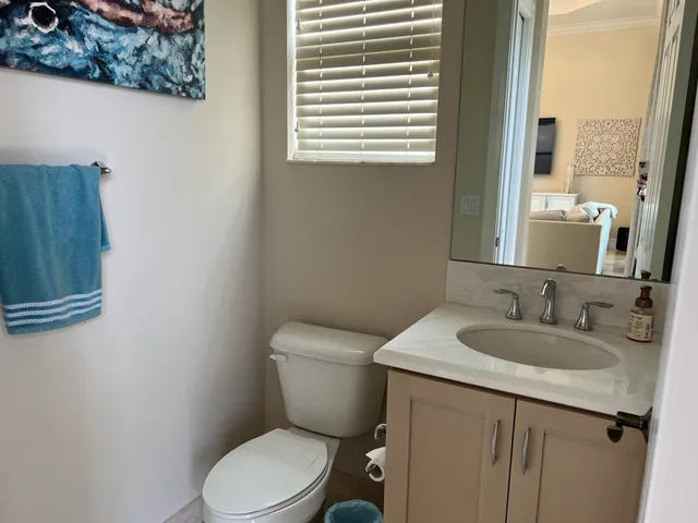 a bathroom with a granite countertop toilet a sink and a mirror