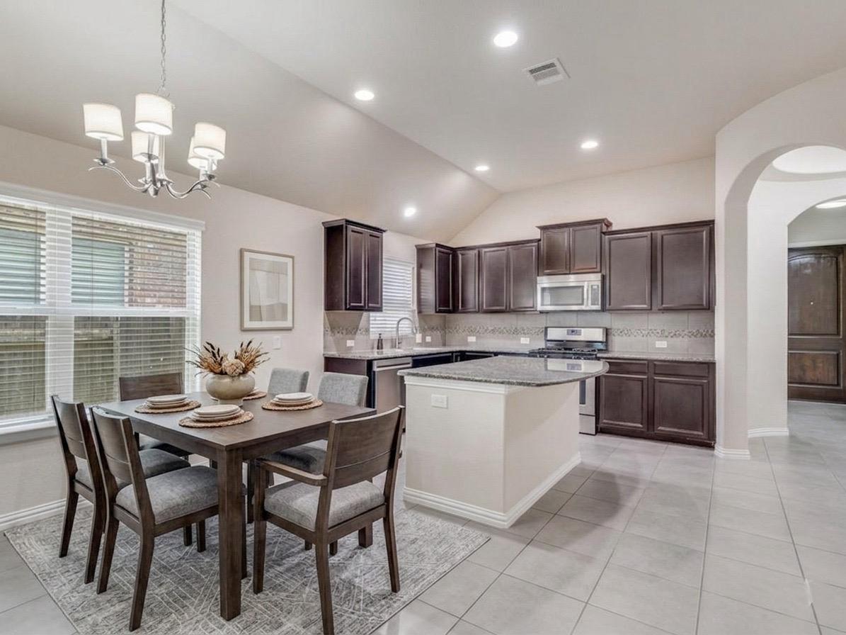 22005 Rhiannon Lane Pflugerville, TX 78660 - Photo 5 of 21 a kitchen with a dining table chairs and white cabinets