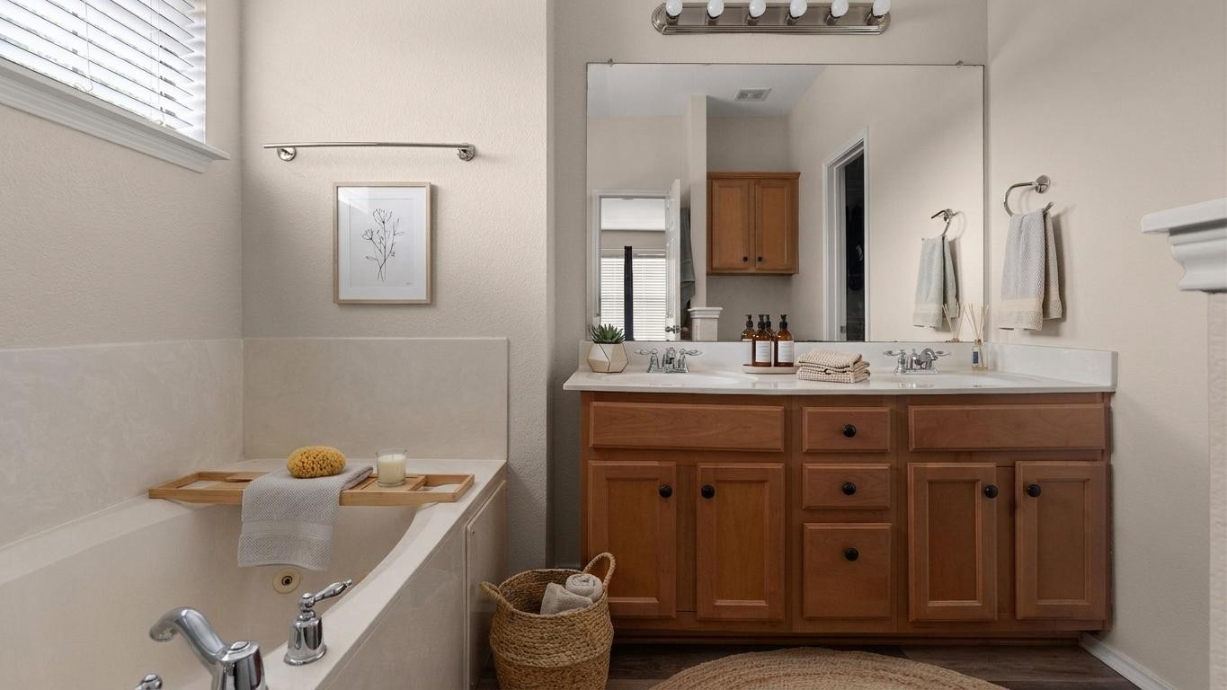 14815 Avery Ranch Boulevard, Unit 1401 Austin, TX 78717 - Photo 17 of 38 Digitally styled. Bathroom featuring a built-in tub with chrome fixtures, a dual-sink vanity with light wood cabinetry, white countertops, and a large wall-mounted mirror