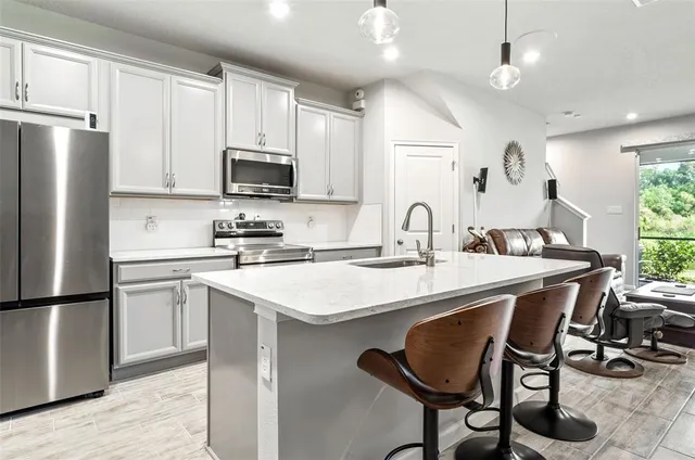 a kitchen with stainless steel appliances granite countertop a sink a stove a refrigerator and island with wooden floor