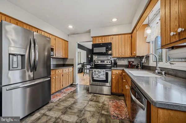 a kitchen with stainless steel appliances granite countertop a refrigerator a stove top oven a sink and dishwasher