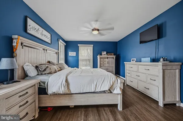 a bedroom with a large bed and a flat tv screen on dresser