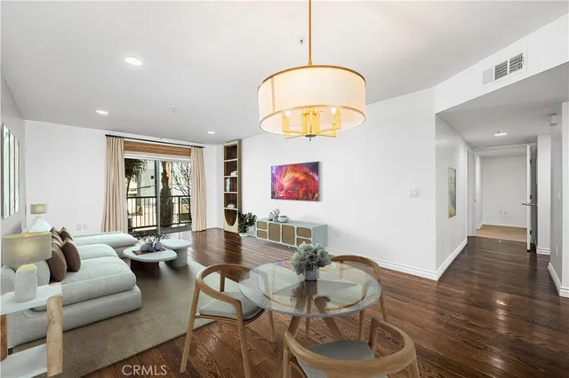 a living room with couches and a dining table with wooden floor
