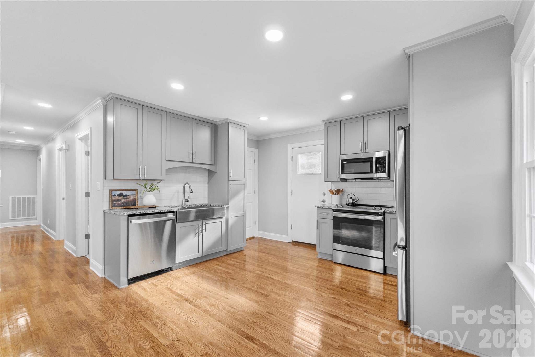 a kitchen with stainless steel appliances granite countertop a stove top oven a sink and dishwasher a refrigerator with wooden floor