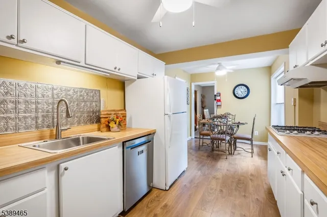 a kitchen with stainless steel appliances granite countertop a sink dishwasher stove and refrigerator with wooden floor