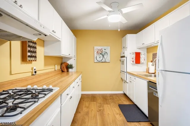a large white kitchen with stainless steel appliances granite countertop a stove and a sink