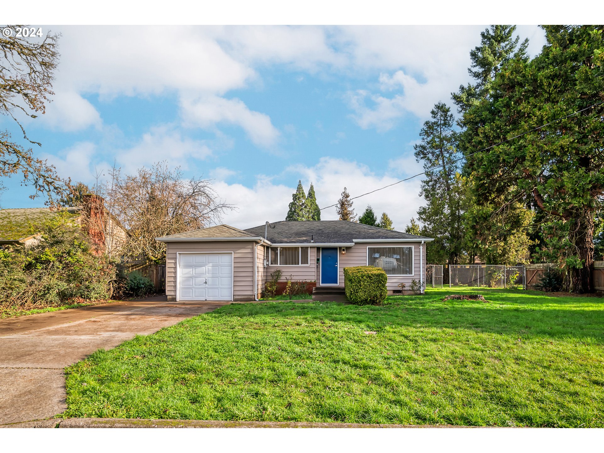 a view of a house next to a big yard and large trees