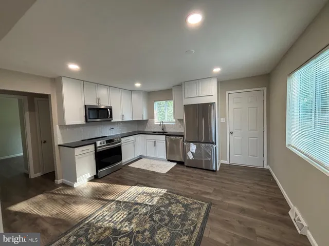 a large kitchen with stainless steel appliances kitchen island granite countertop a refrigerator and a stove top oven