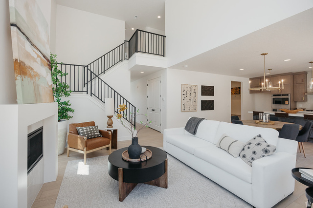 5902 Canyon Rim Road, Unit 620 Lehi, UT 84048 - Photo 16 of 78 Open-concept living space featuring a two-story entryway with iron railings, a contemporary fireplace with a white mantel, high ceilings, recessed lighting, and wood-finish flooring