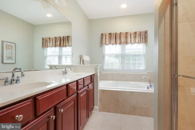 a bathroom with a granite countertop sink a bathtub and next to a window