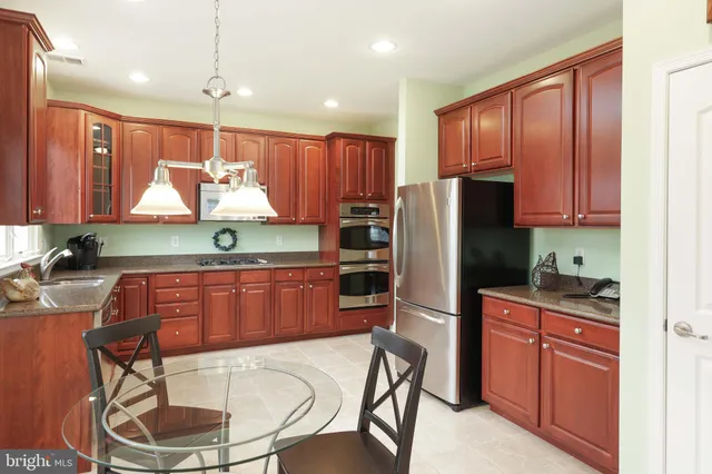 a kitchen with granite countertop wooden cabinets stainless steel appliances and a refrigerator