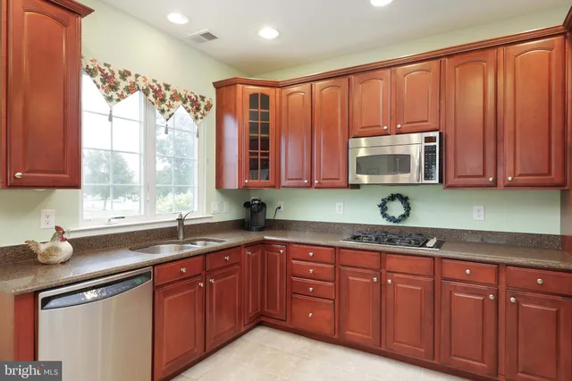 a kitchen with stainless steel appliances granite countertop wooden cabinets a sink and a window