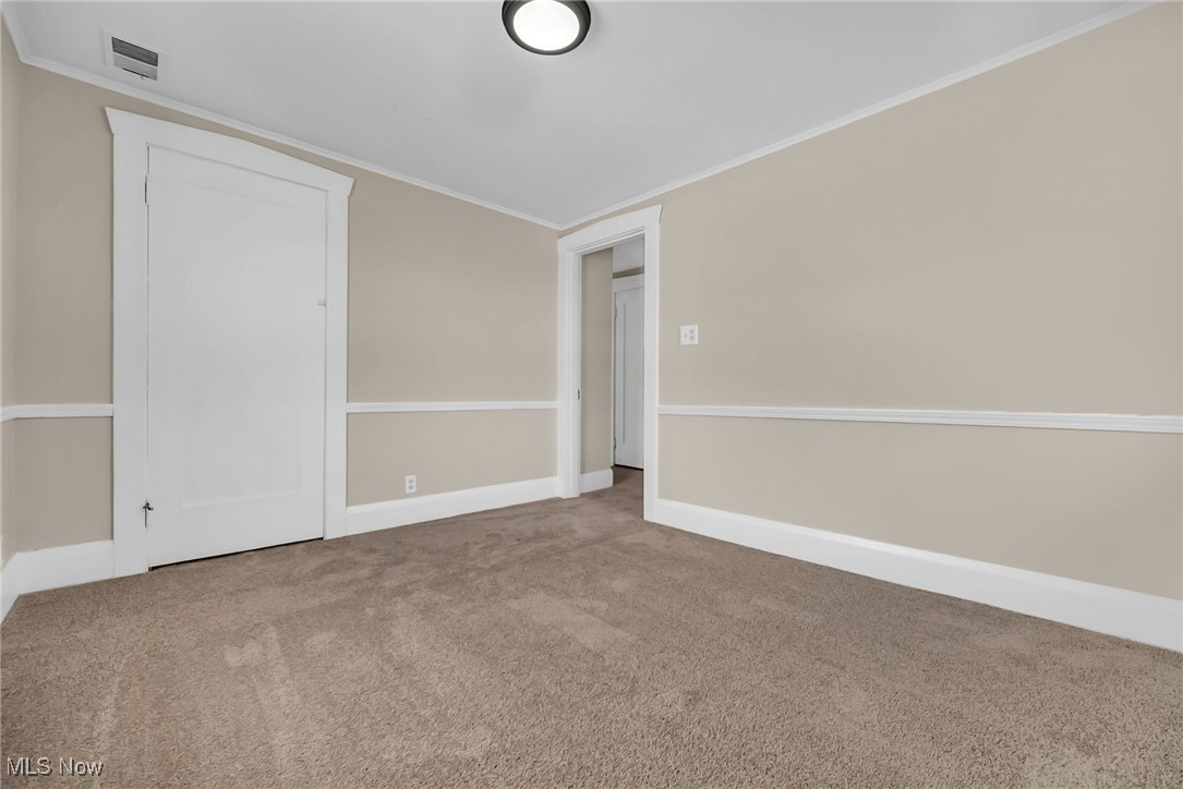 404 Niles Vienna Road Vienna, OH 44473 - Photo 31 of 48 Carpeted spare room featuring visible vents, crown molding, and baseboards