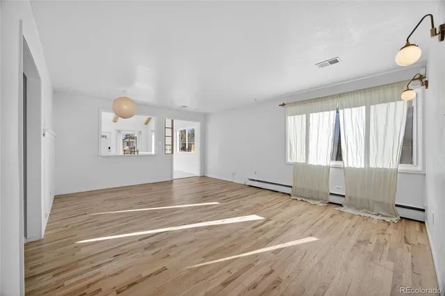 a view of an empty room with a window and wooden floor