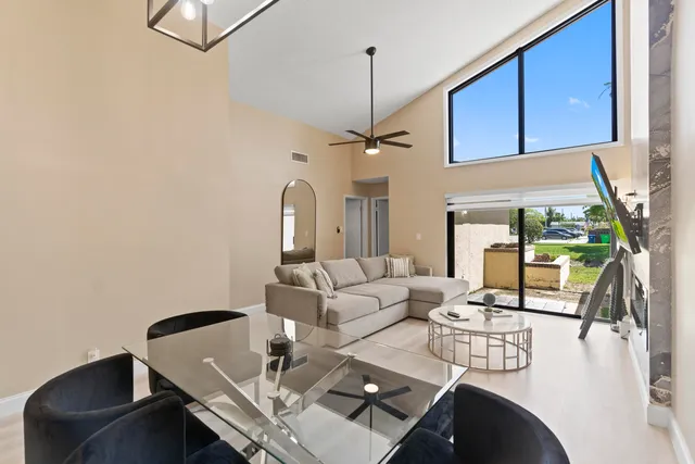 a living room with couches a fireplace and a dining table with garden view