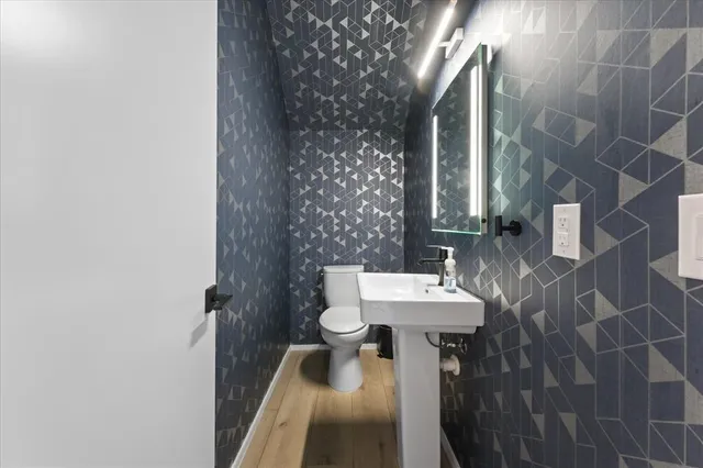 a view of a hallway with wooden floor and a bathroom